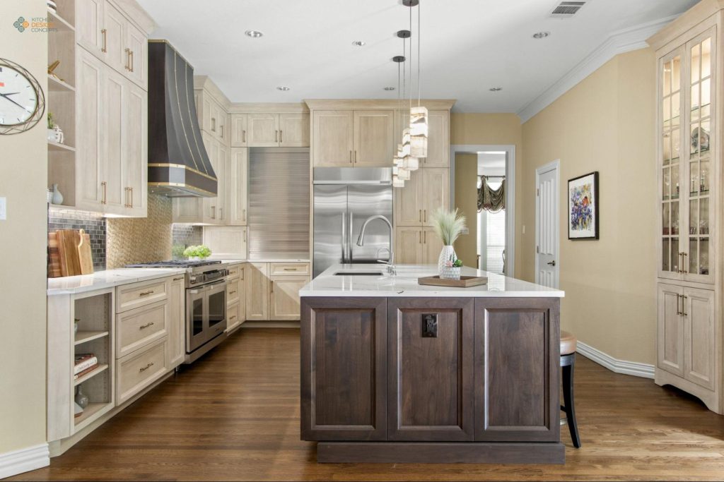 Dallas kitchen remodel with bleached wood cabinetry, dark walnut island, black and gold statement range hood, metallic tile backsplash, and stainless Sub-Zero refrigerator — Kitchen Design Concepts